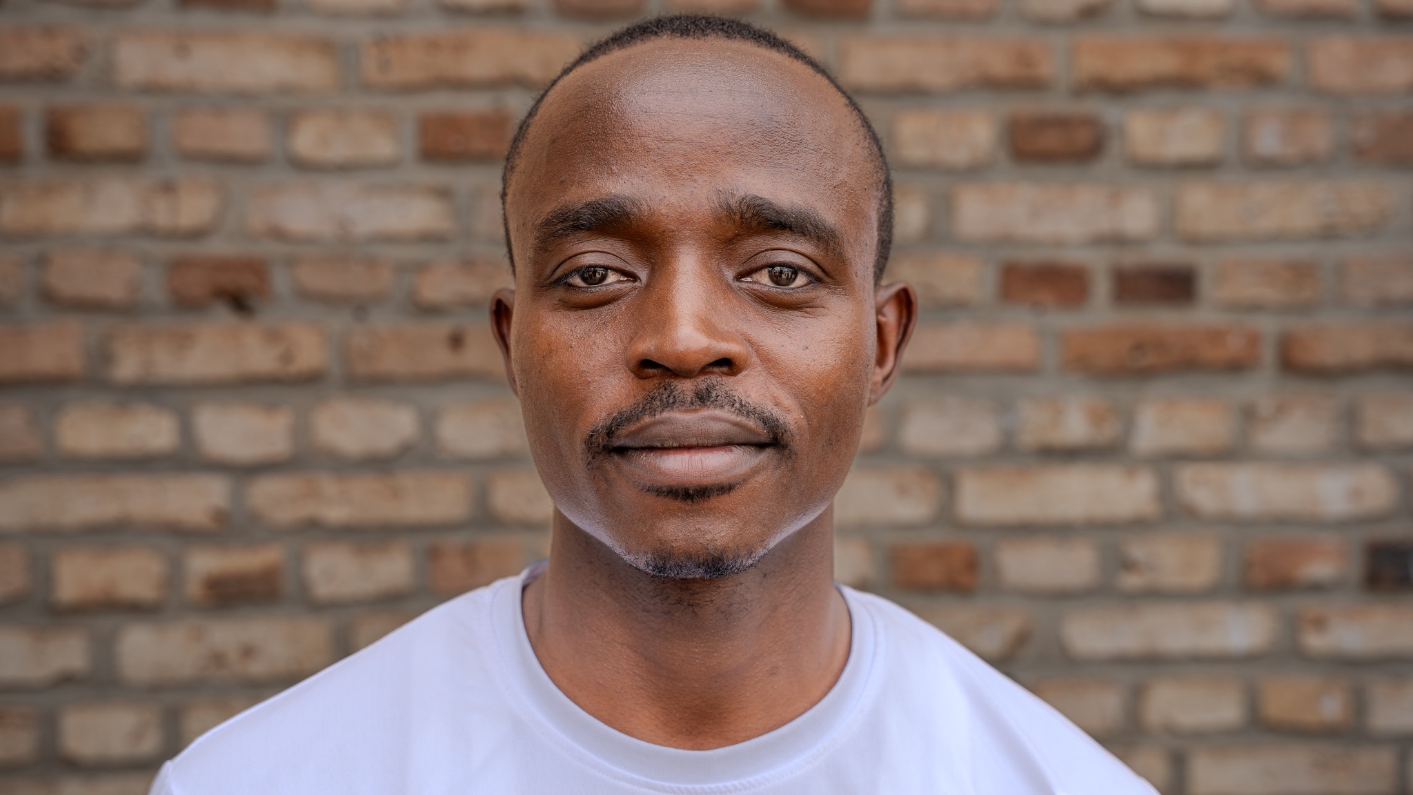 A man photographed against a brick wall in Rwanda